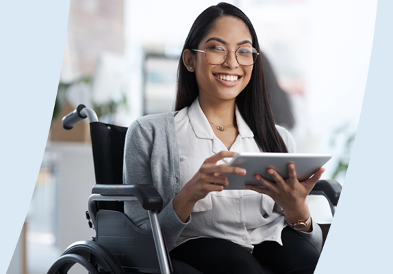 Person smiling, holding a tablet and sitting in a wheelchair